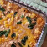 Savory honey BBQ chicken dip in glass dish topped with cheddar and chives.