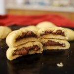 Two nutella stuffed cookies cut open and stacked on top of one another.