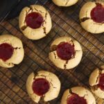 Cookies with a jelly filled indent on top sitting on a wire rack.