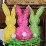 three fabric bunnies in bright colors with white tails.