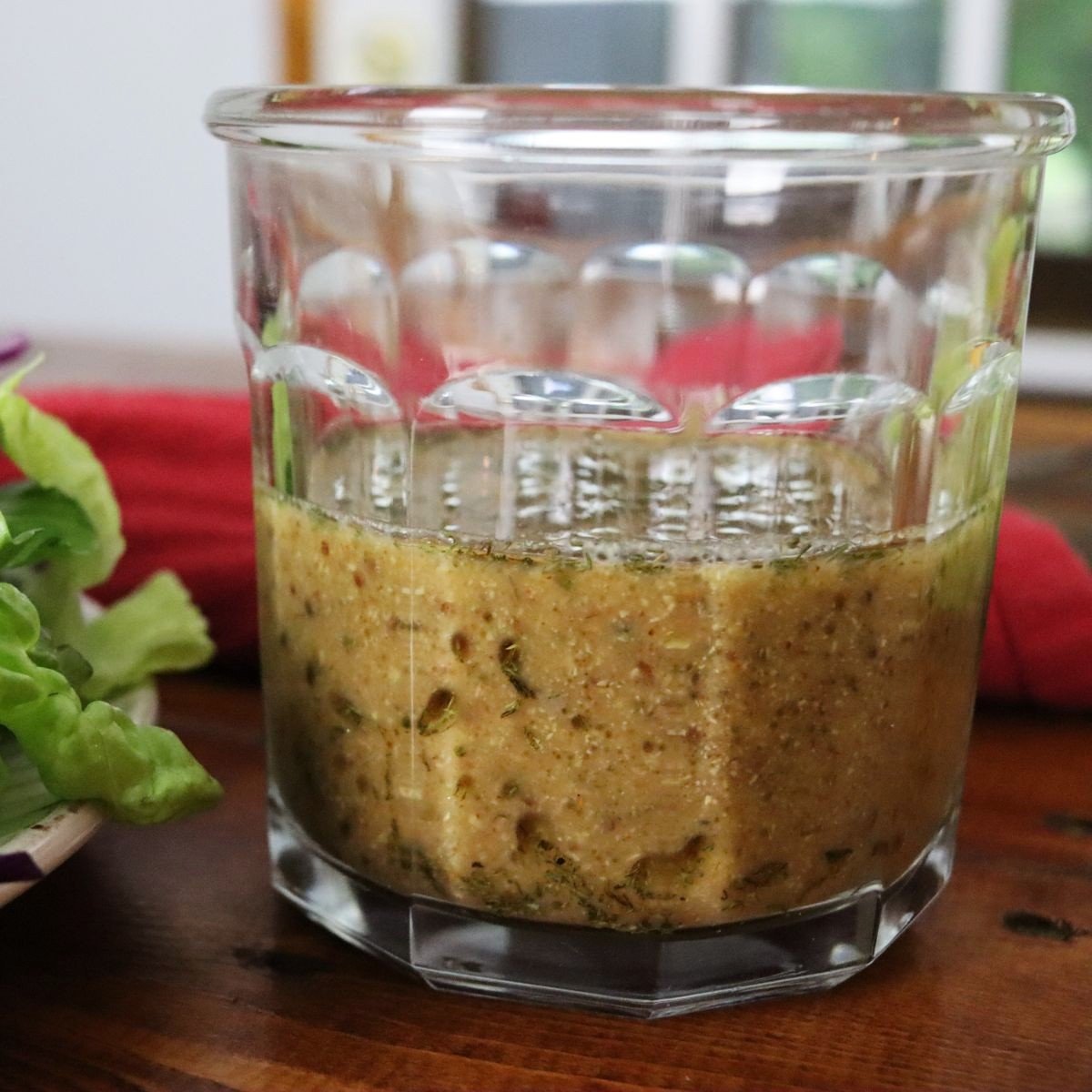 glass jar with tangy mustard salad dressing in it sitting on a table.