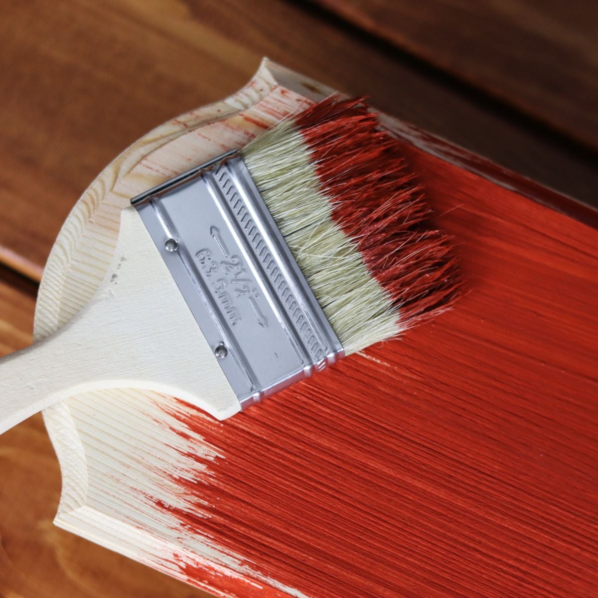 Partially painted wooden board with a paint brush laying on it.