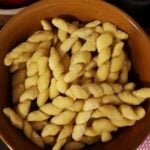 Handmade pasta in twist shapes in a brown bowl.