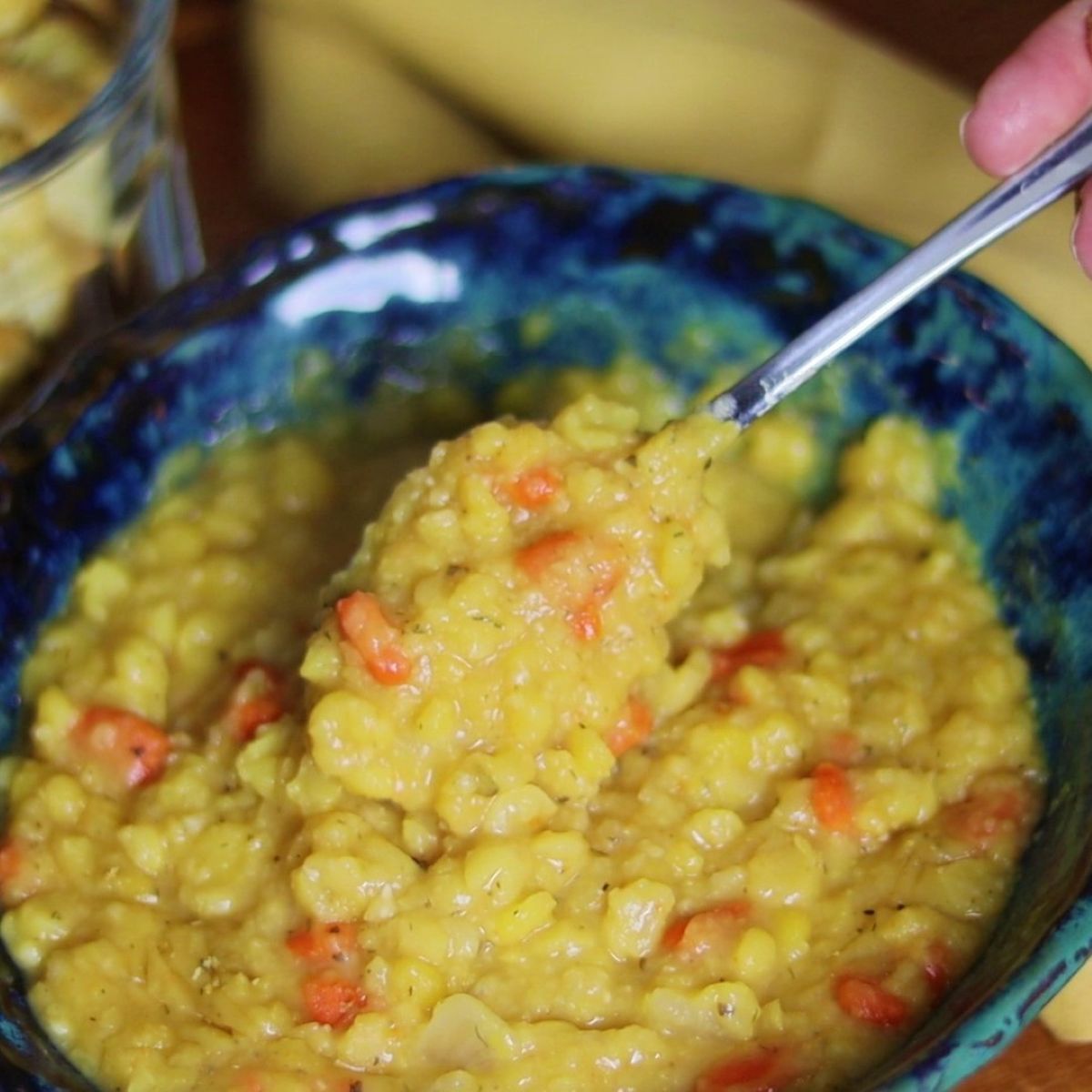 bowl of yellow split pea soup with a spoonful being removed from it.