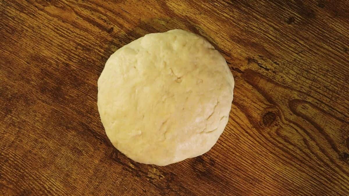 Ball of dough sitting on a wooden surface.