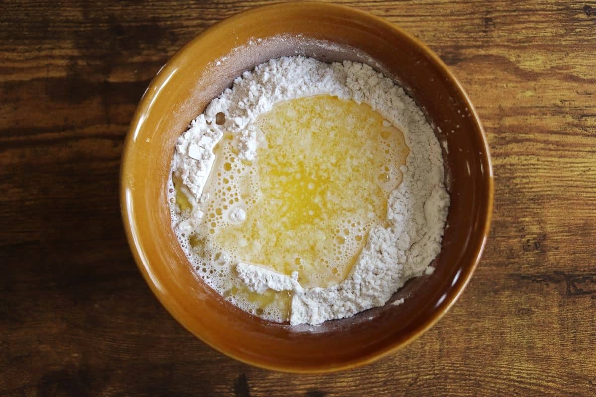Flour in a bowl with a butter mixture sitting in a well in the center of it.