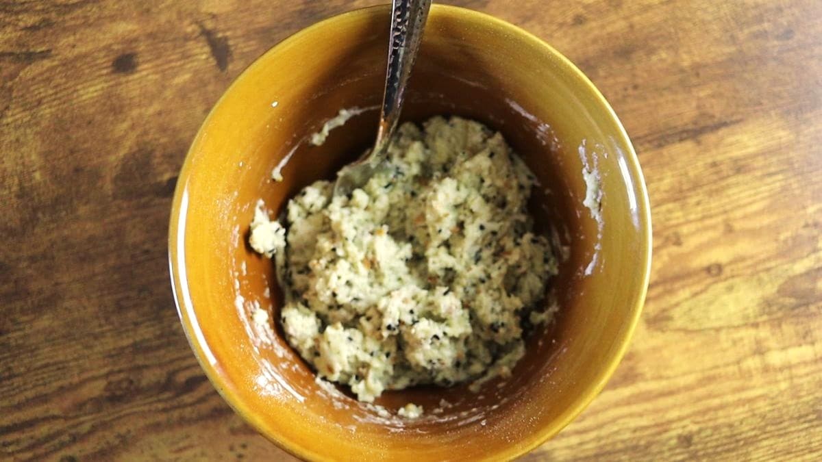 Batter with seeds visible in it in a bowl with a fork resting in it sitting on a wooden surface.