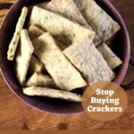 Rectangular crackers in a purple bowl on a wooden surface with text overlay on the image that reads 'everything crackers recipe, stop buying crackers, and sustainableslowliving.com.