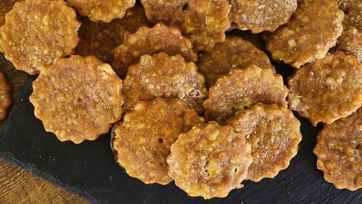 Round, scalloped edge crackers spread out on a dark surface.