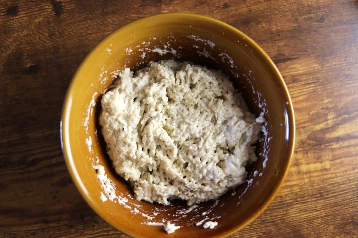 Dough mixture in a bowl on a wooden surface.