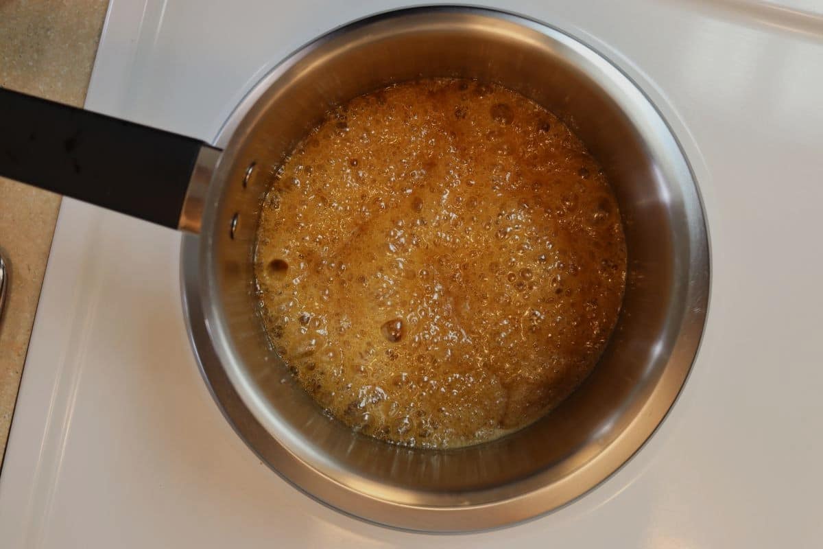 Brown sauce simmering in a small saucepan on a stovetop.