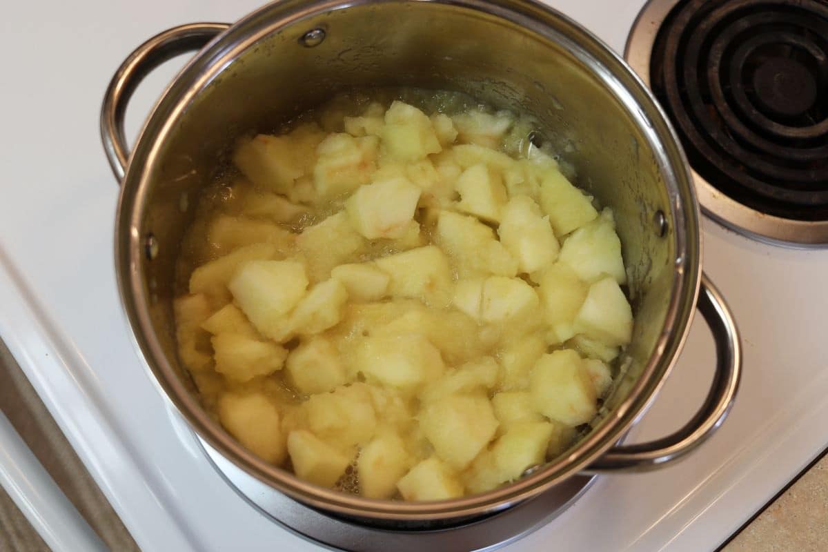 Apple chunks simmering in a pot on a stovetop.