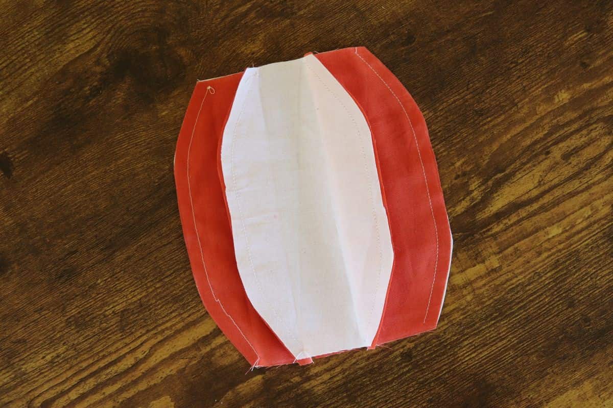 White and orange oval shaped fabric panels sewn together in a circle.