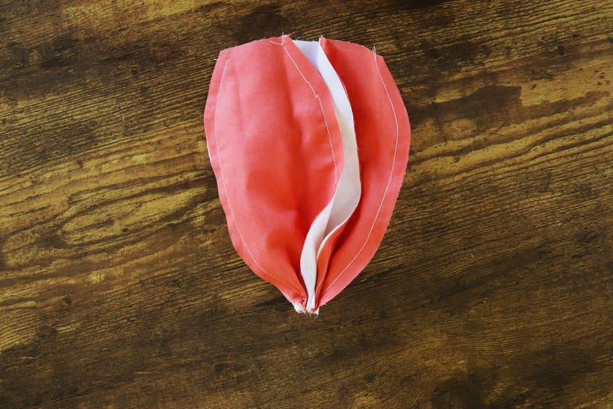 White and orange ovel shaped fabric panels sewn together in a circle and gathered at one end.