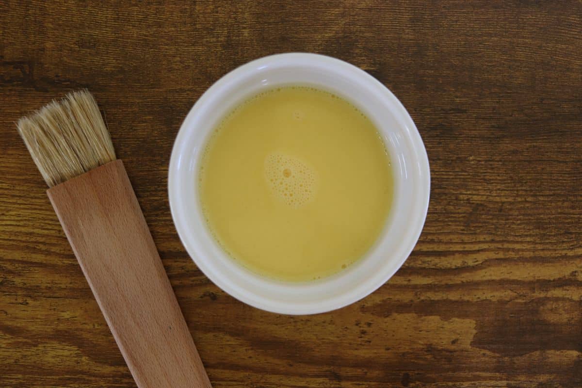 Yellow liquid in a white bowl on a wooden surface.
