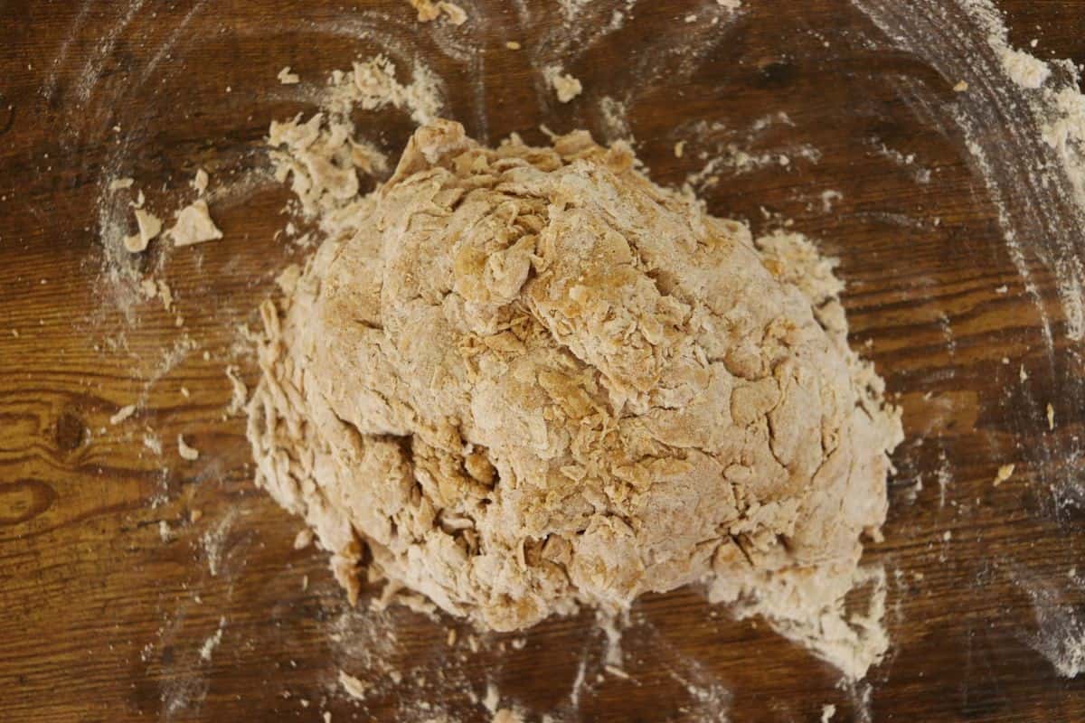 Orange colored shaggy dough on a floured wooden surface.