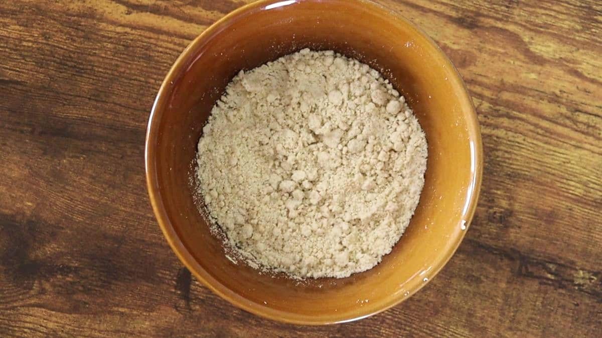 Flour mixture with a texture like coarse sand in a bowl on a wooden surface.