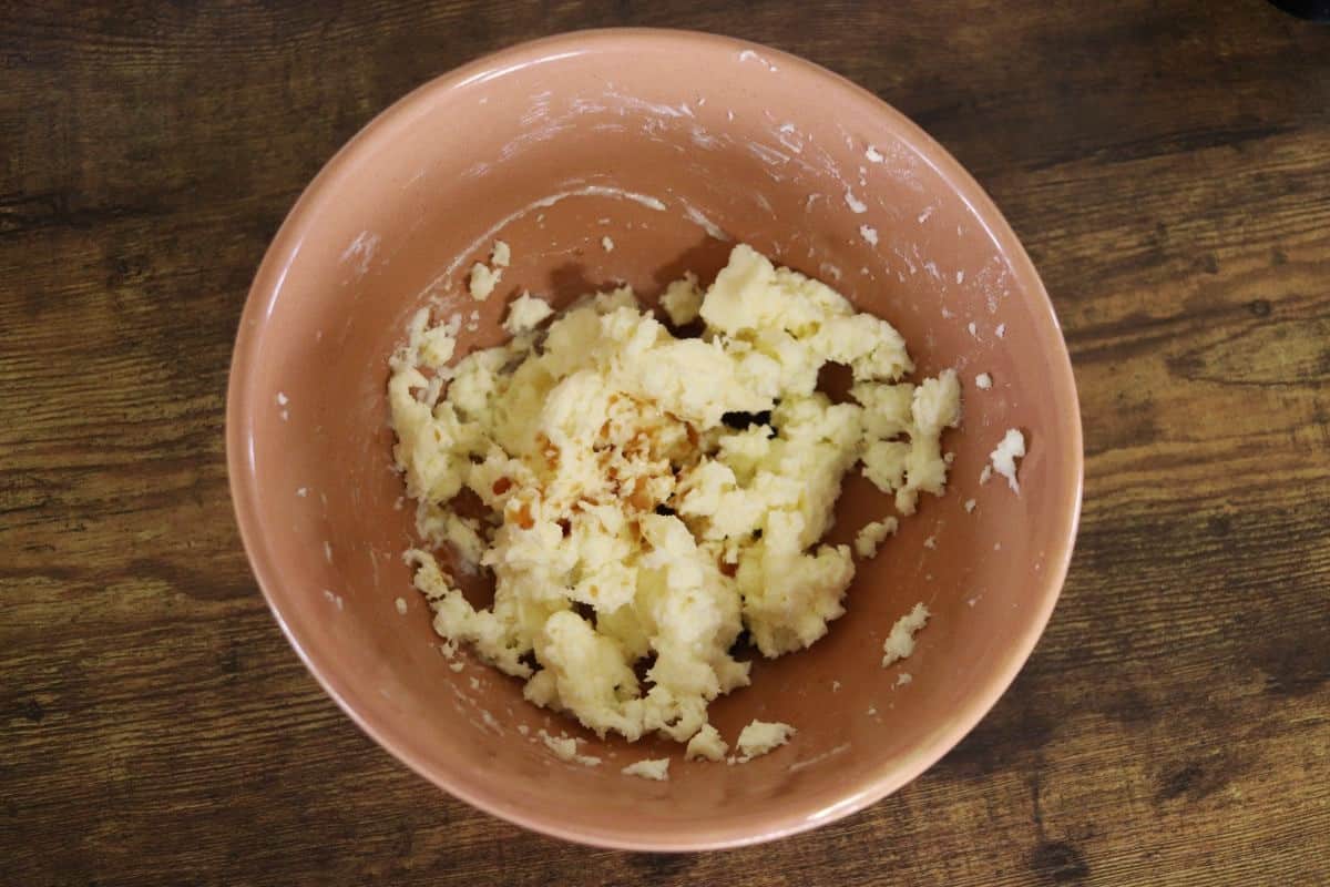 Cream butter in a bowl with a brown liquid poured over it.