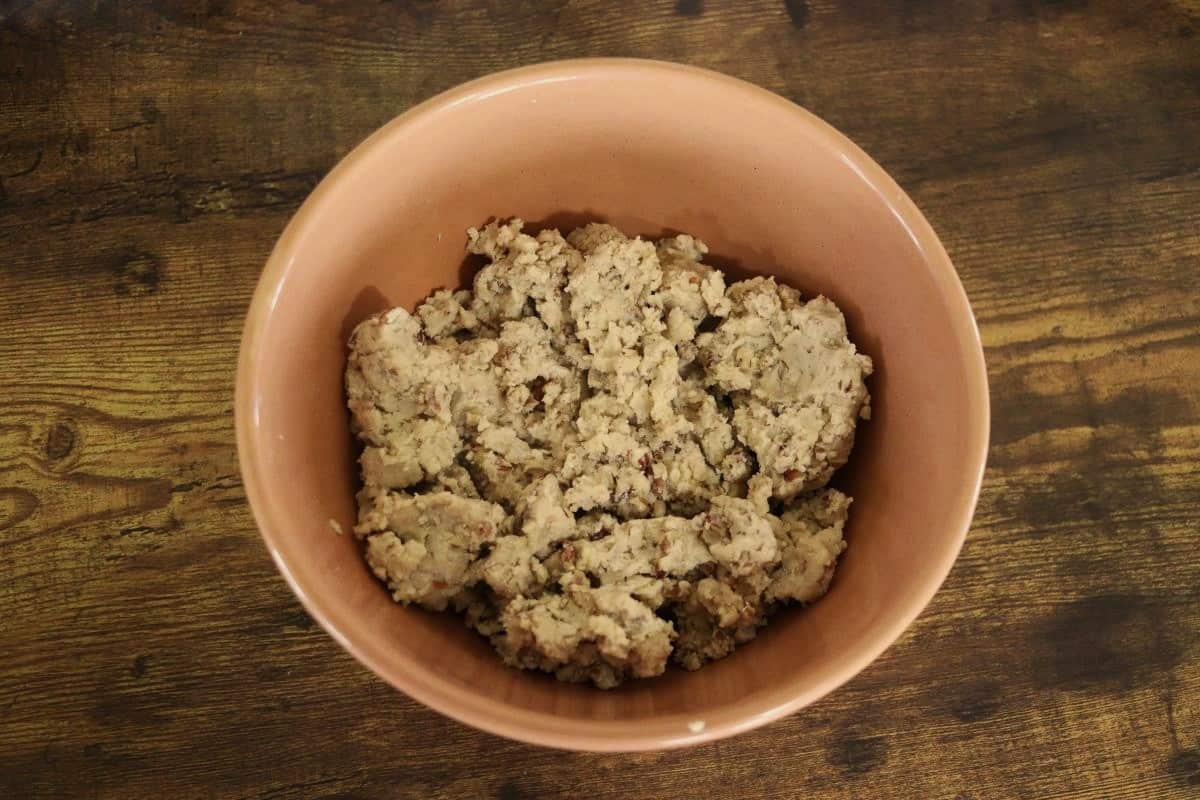 Tan colored batter in a bowl sitting on a wooden surface.