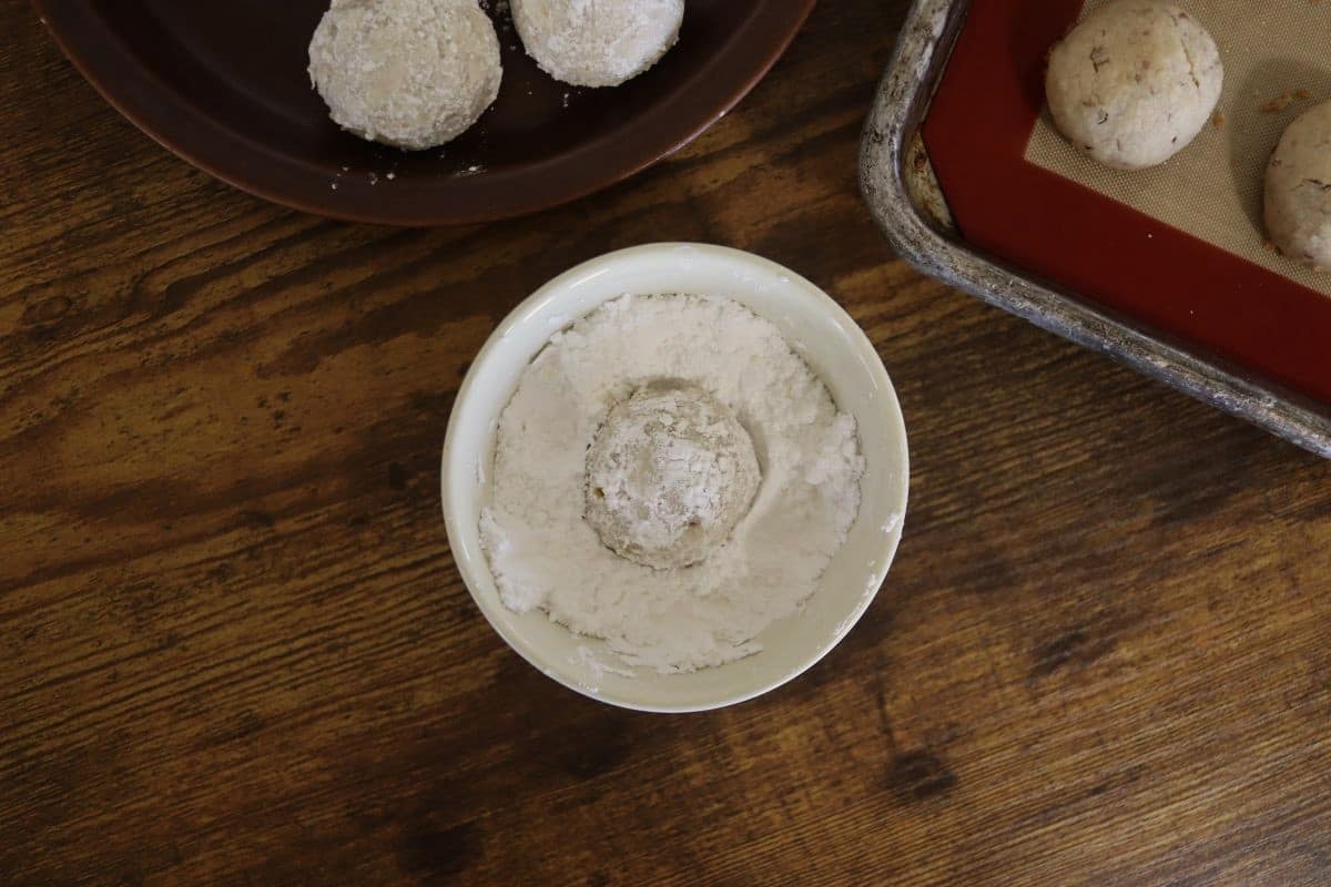 Ball of dough in a small dish of white powder.