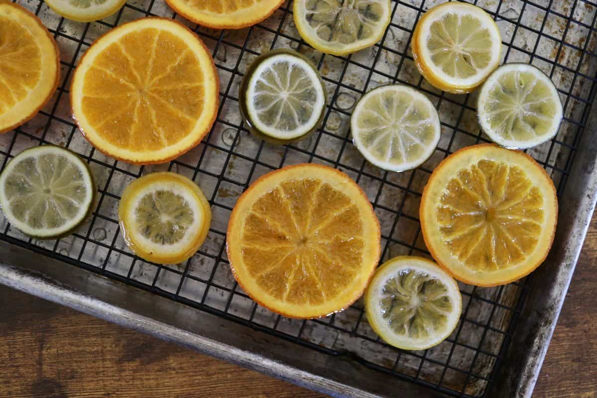 Cooked orange, lemon, and lime slices on a wire rack sitting in a baking sheet.