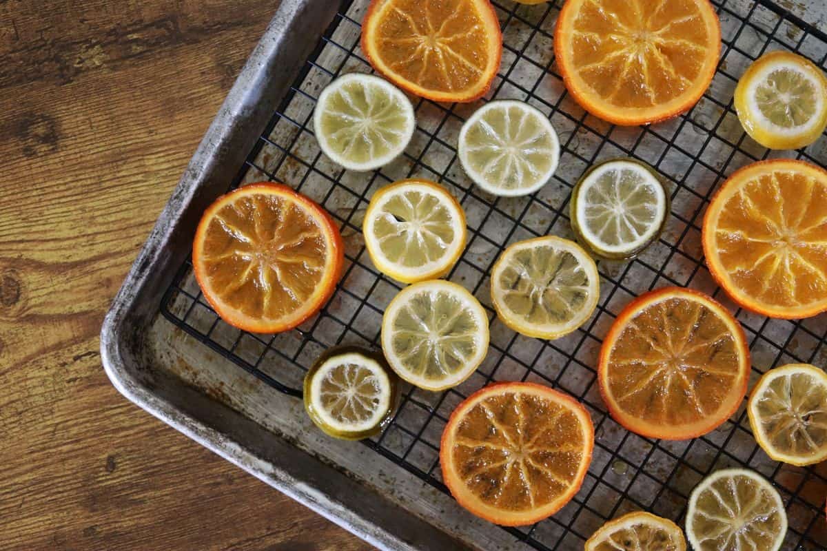 Transparent citrus slices, orange, lemon, and lime, laid out on a wire rack sitting in a baking sheet.