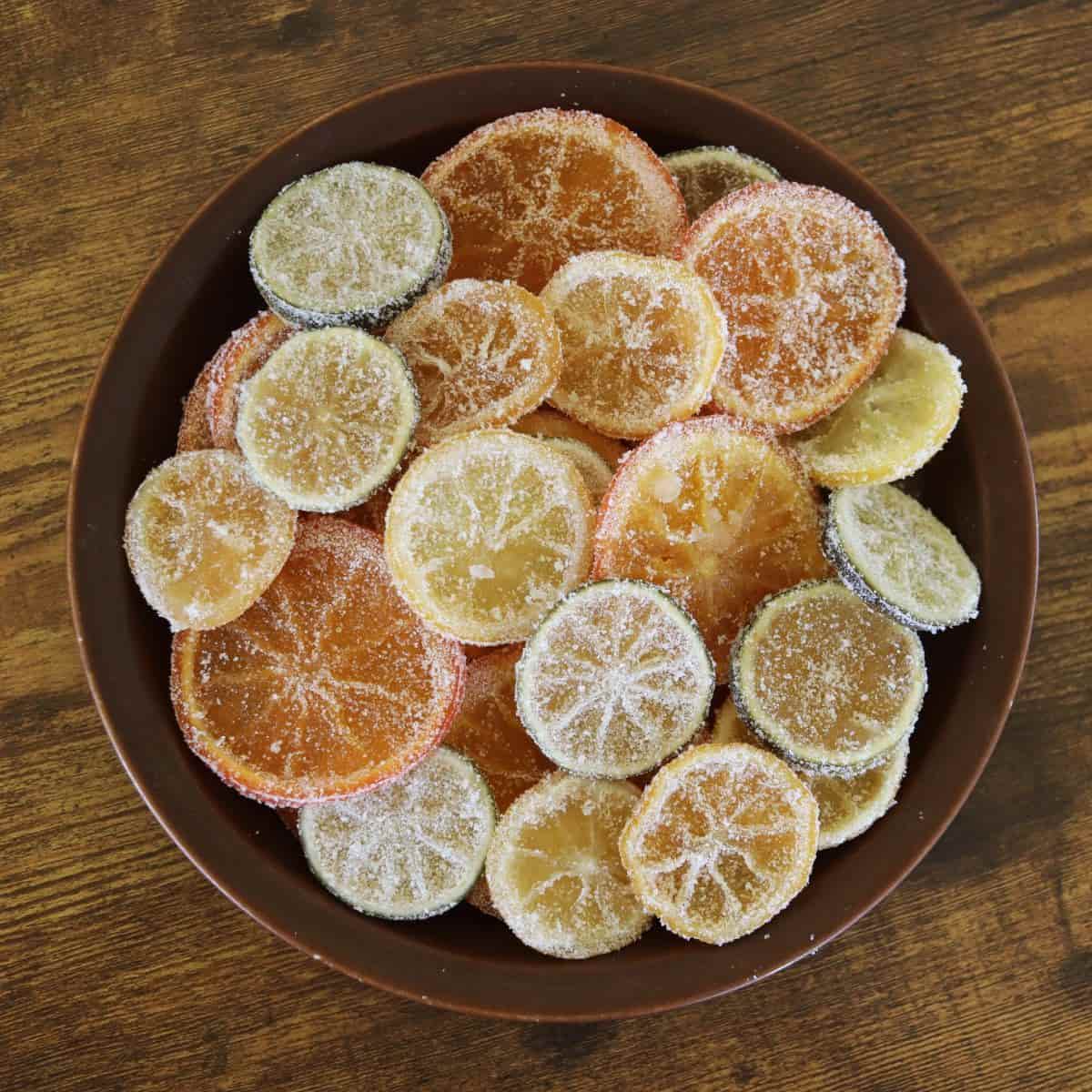 A plate stacked high with candied citrus slices that are coated in sugar.