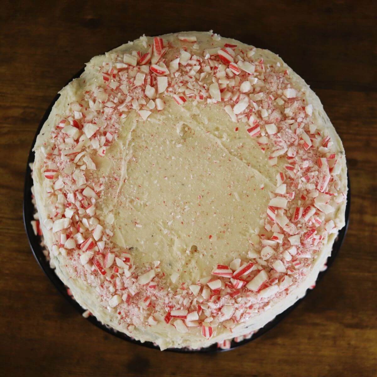 The top of a round cake covered in white icing and crushed peppermint candy.