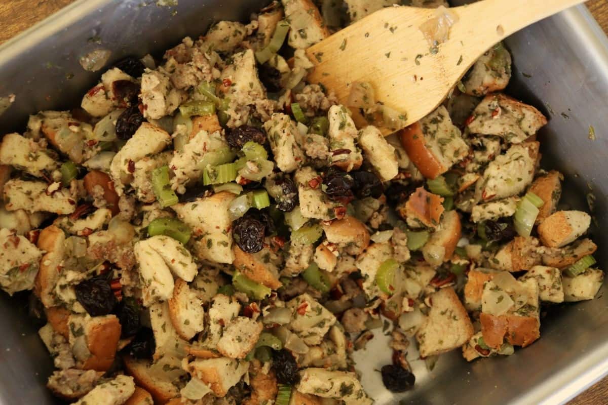 Uncooked stuffing, with celery, onions, cherries, sausage, pecans, and herbs, tossed together in a pan.