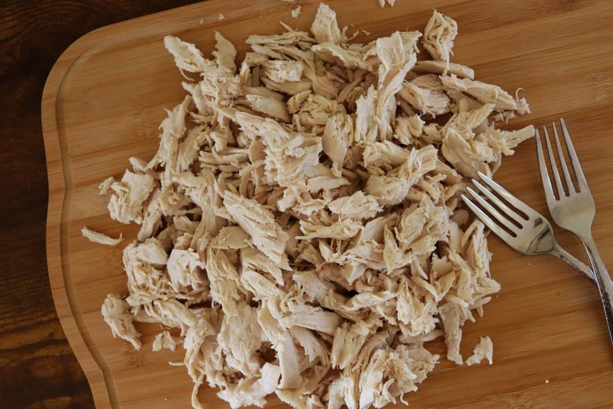 Shredded, cooked turkey on a bamboo surface.