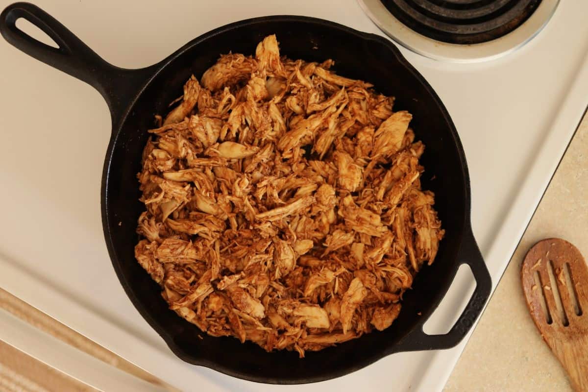 Turkey, cooked and shredded, and coated in bbq sauce in a cast iron skillet.