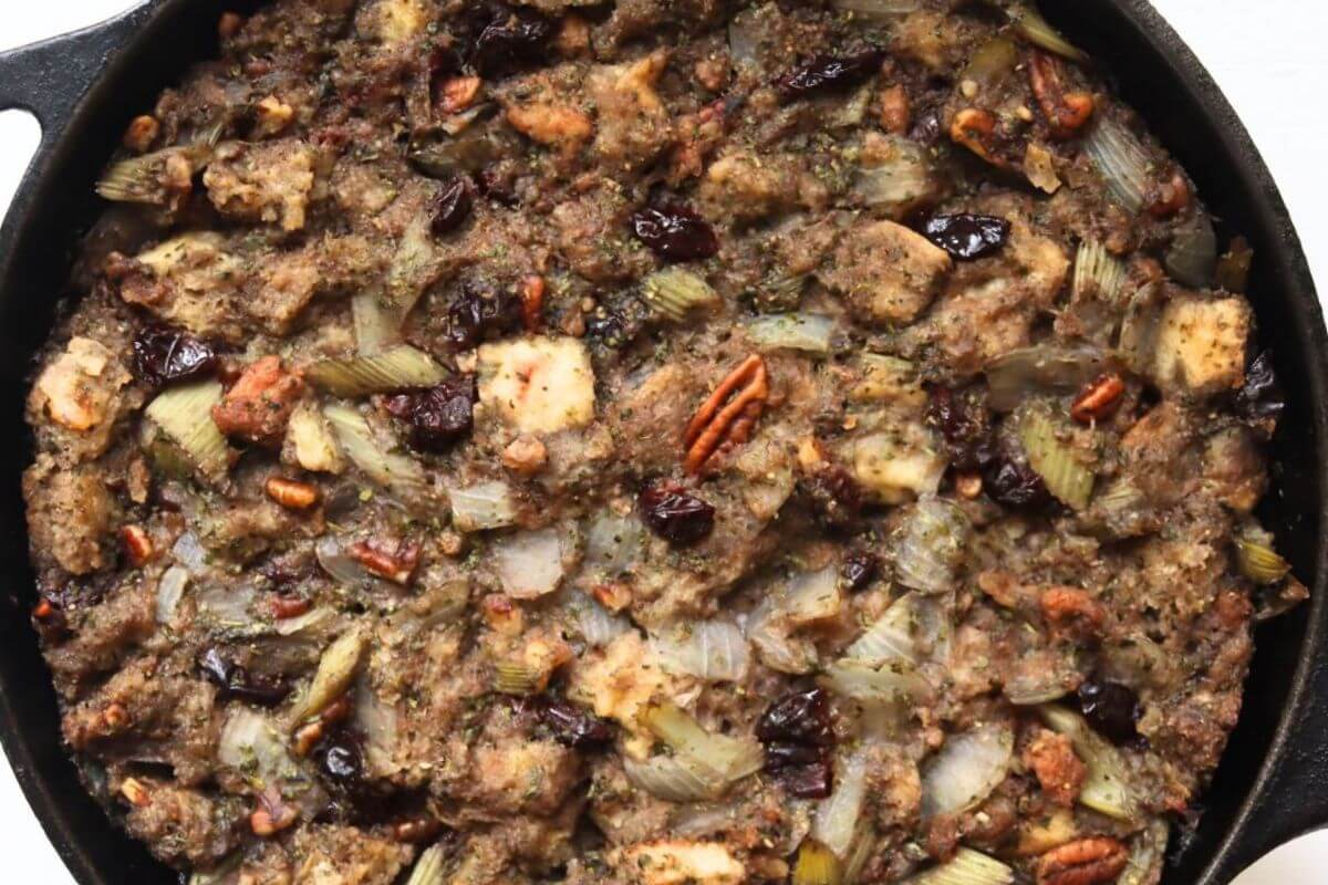 Turkey dressing made with bread cubes, savory sausage, pecans, and dried cherries in a cast iron skillet.
