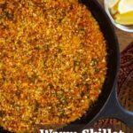 A cast iron pan filled with a crumbly, golden-orange dish in it and text overlay that reads 'warm skillet crab cake dip'.