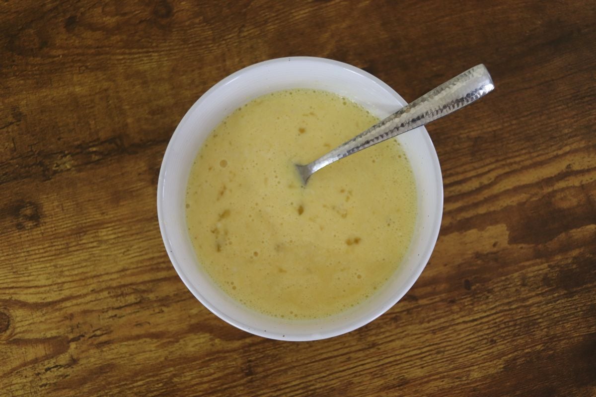 Scrambled egg mixture in a white bowl with a fork resting in it.