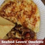 An omelette with smoked paprika and shredded cheese on top sitting on white plate with homefried and semolina toast on the plate next to it. Text overlay reads 'seafood lovers' omelette' and 'simple. elegant. delicious.'.