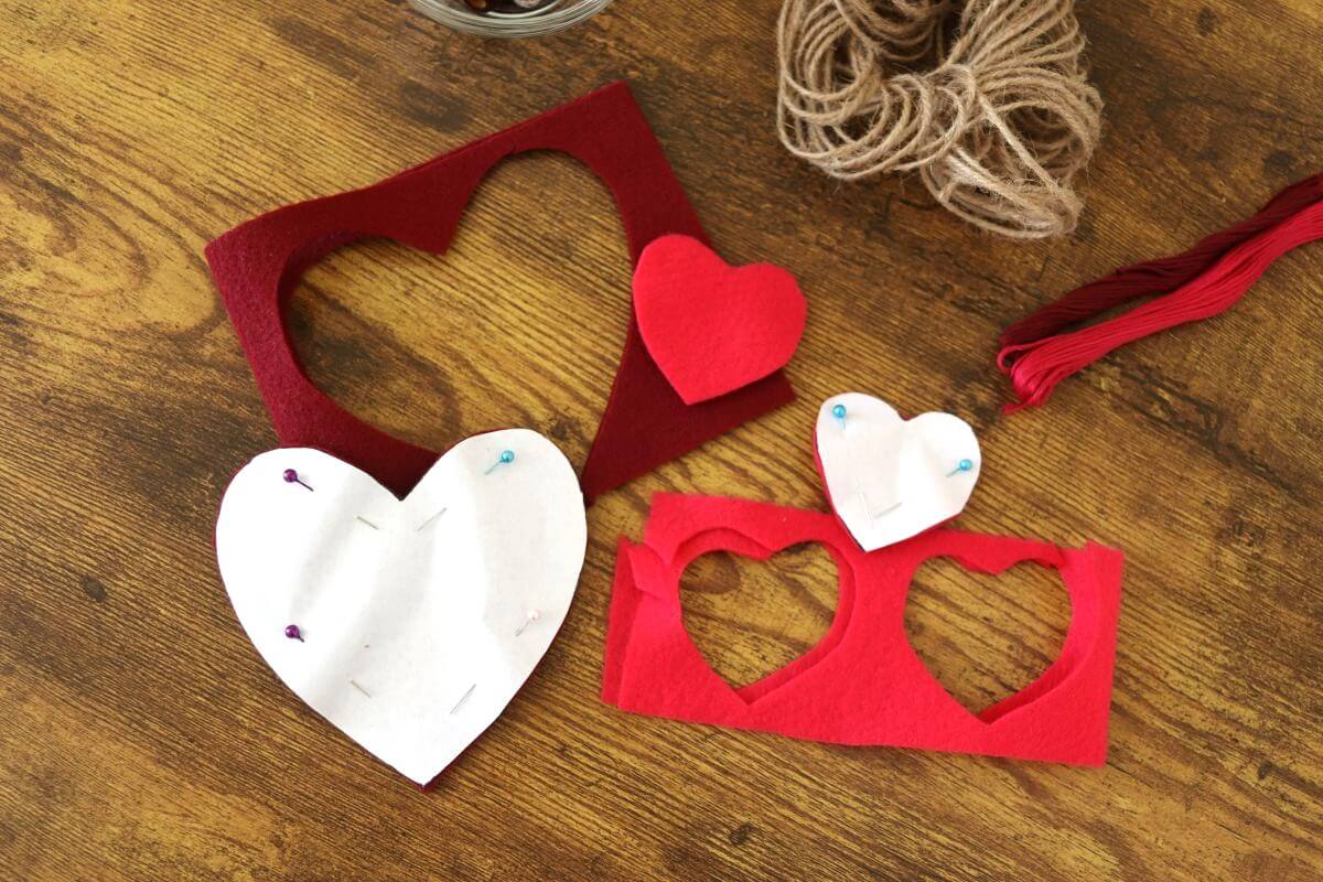 White paper hearts pinned to felt cutouts with felt next to them and twine and thread visible to the side of them.