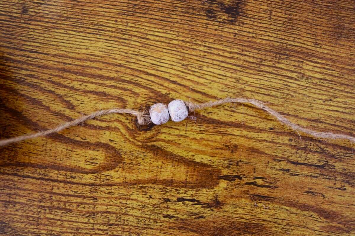 Jute twine with two beads strung on it with a knot tied on either side of them.