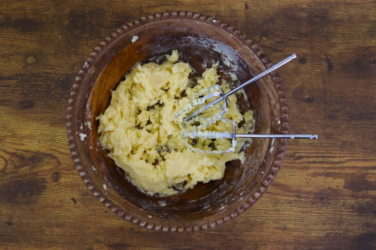 Creamed butter and sugar in a wooden bowl with beaters in it.