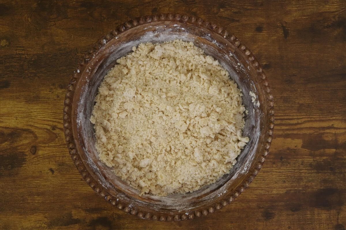Crumbly dough mixture on a wooden bowl.