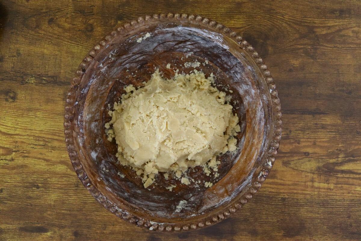 A lump of dough in a wooden bowl.