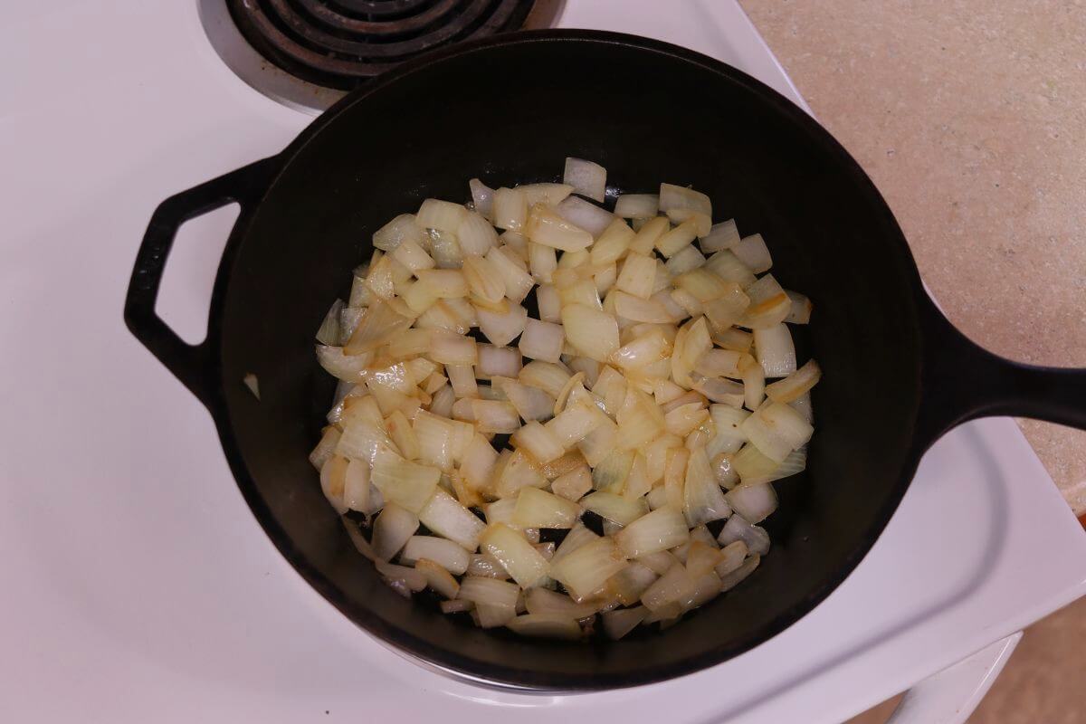 Chopped, partially cooked onions in a cast iron pot.
