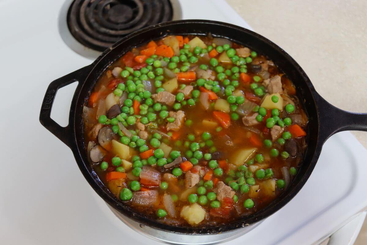 A cast iron pot full of vegetables and pork cubes in broth.