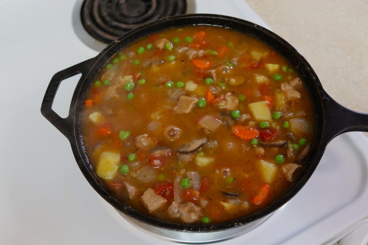A cast iron pot of pork stew on a stovetop.