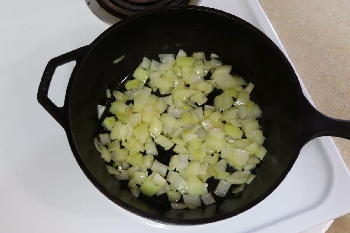 Chopped onions cooking in a cast iron skillet.