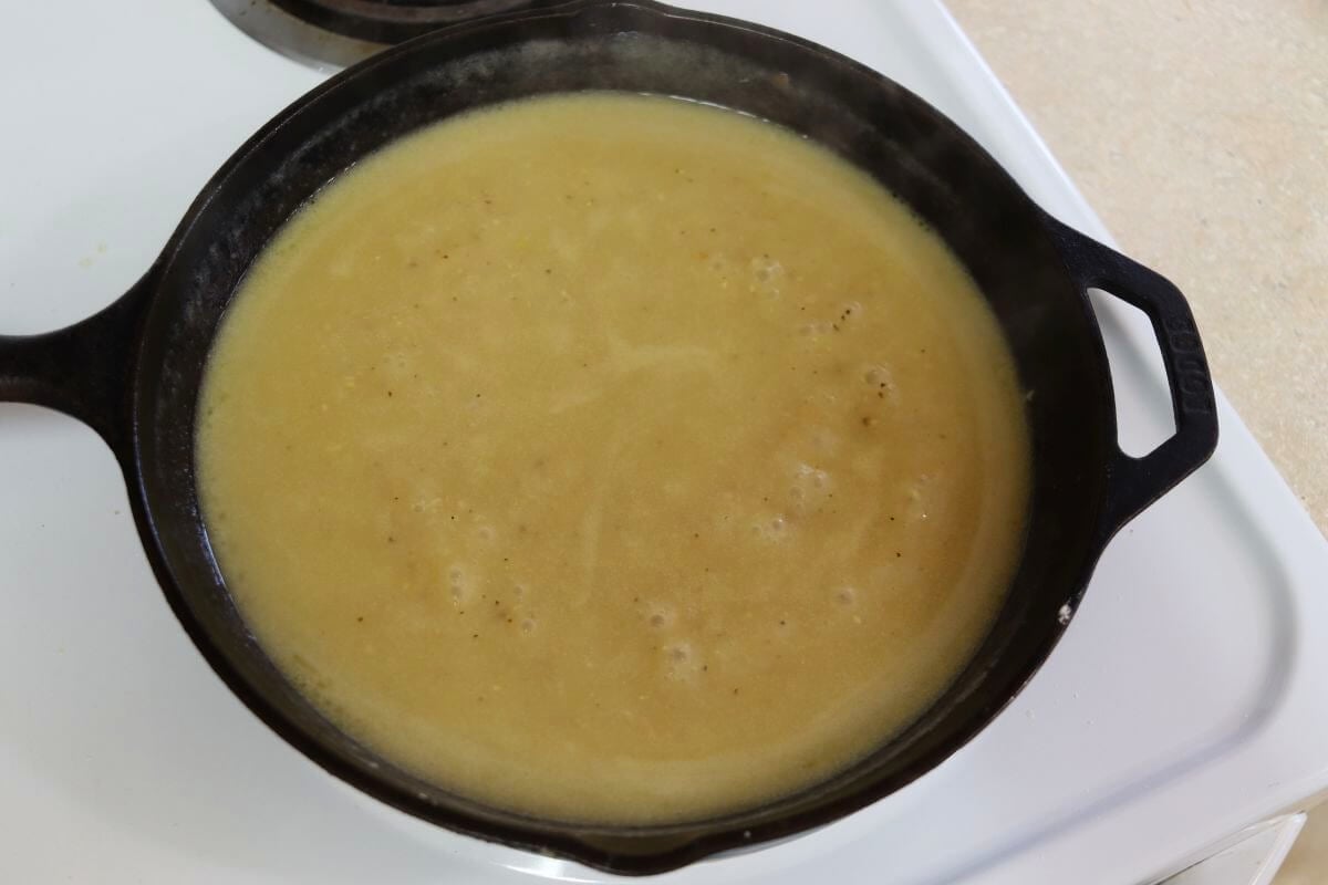 Chicken gravy simmering in a cast iron skillet.