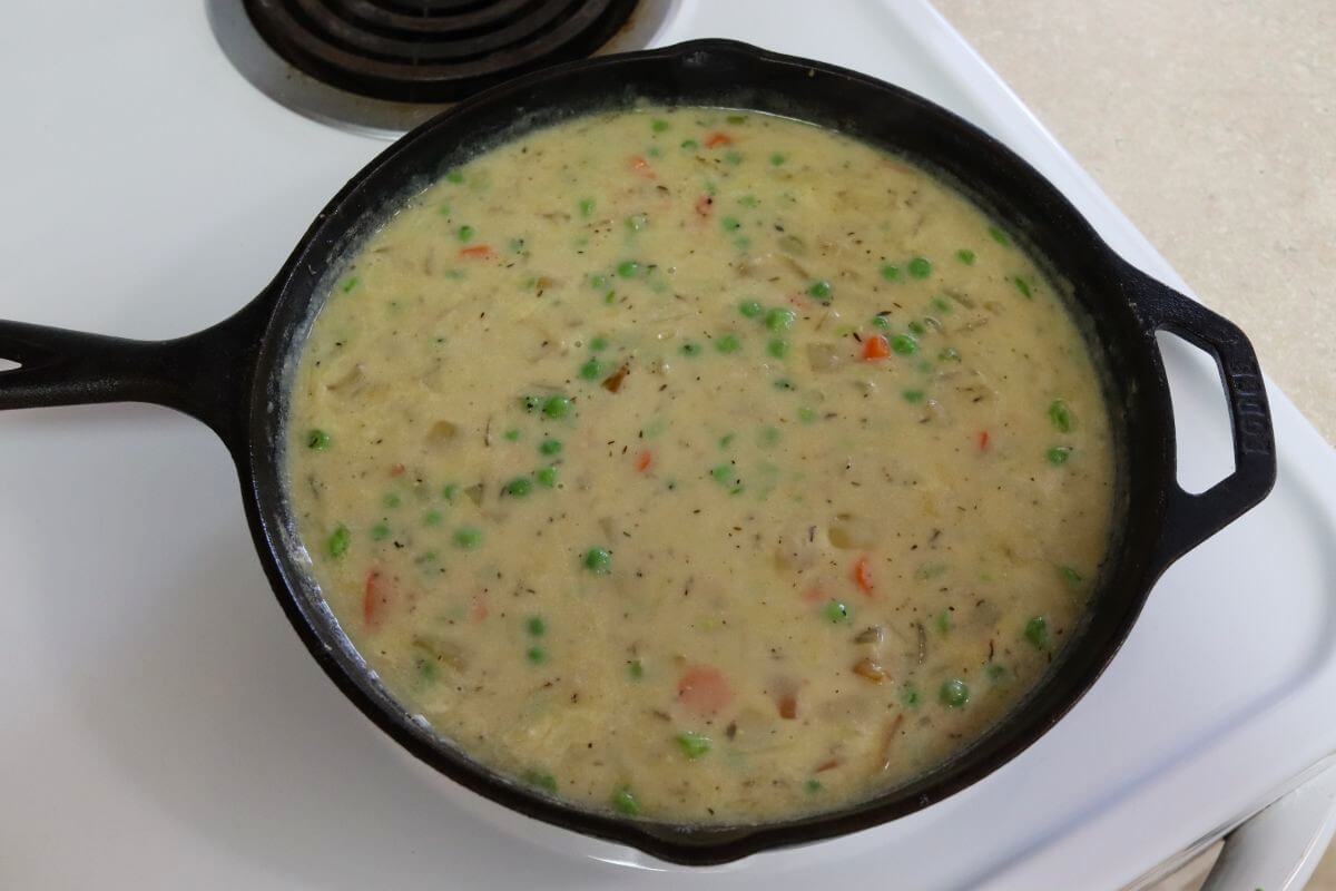 Cream sauce finished with vegetables in a cast iron skillet after stirring in the cream.