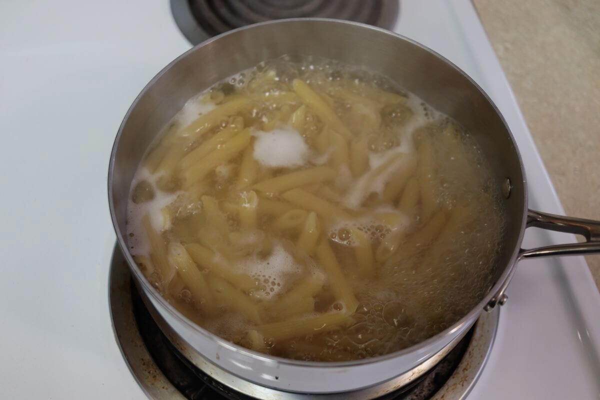 Penne pasta simmering in a saucepan.