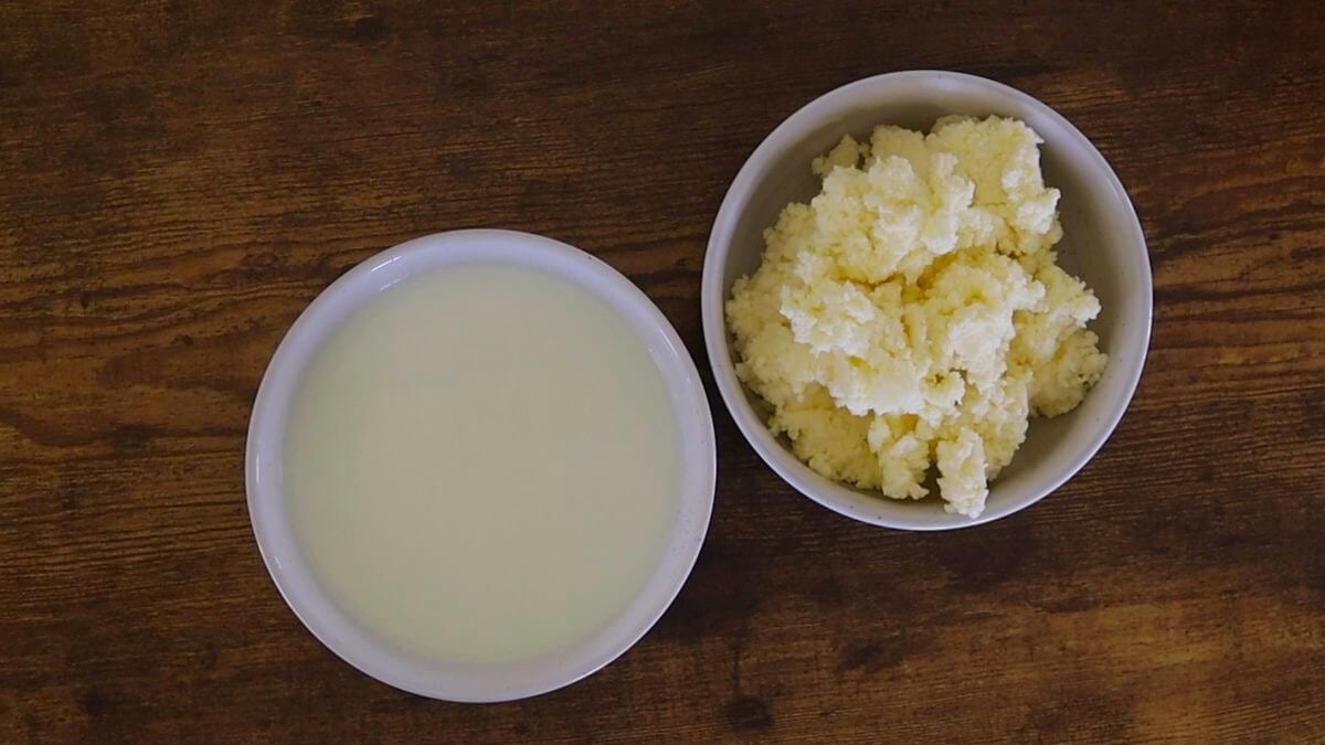 A bowl of buttermilk and a bowl of butter on a wooden table.