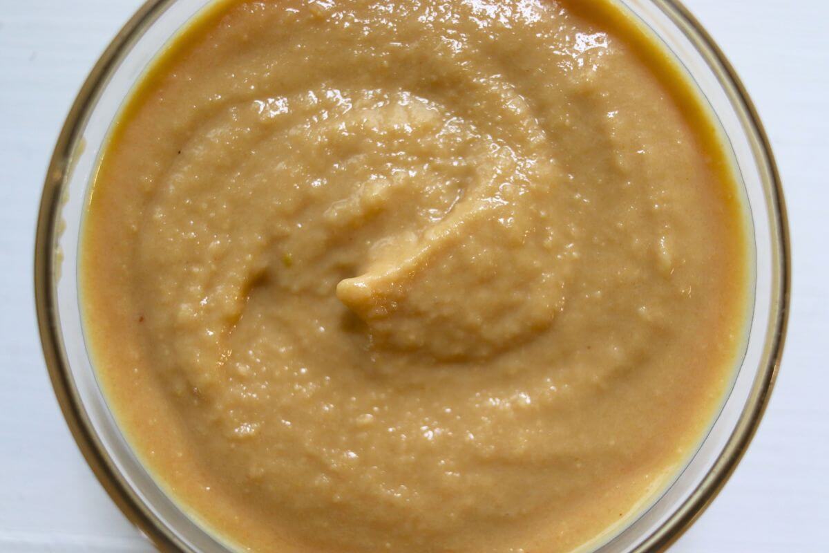 Smooth homemade Dijon mustard served in a clear glass bowl.