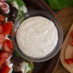 White sauce in a small dish with chopped tomatoes, lettuce, and chopped beef visible next to it.